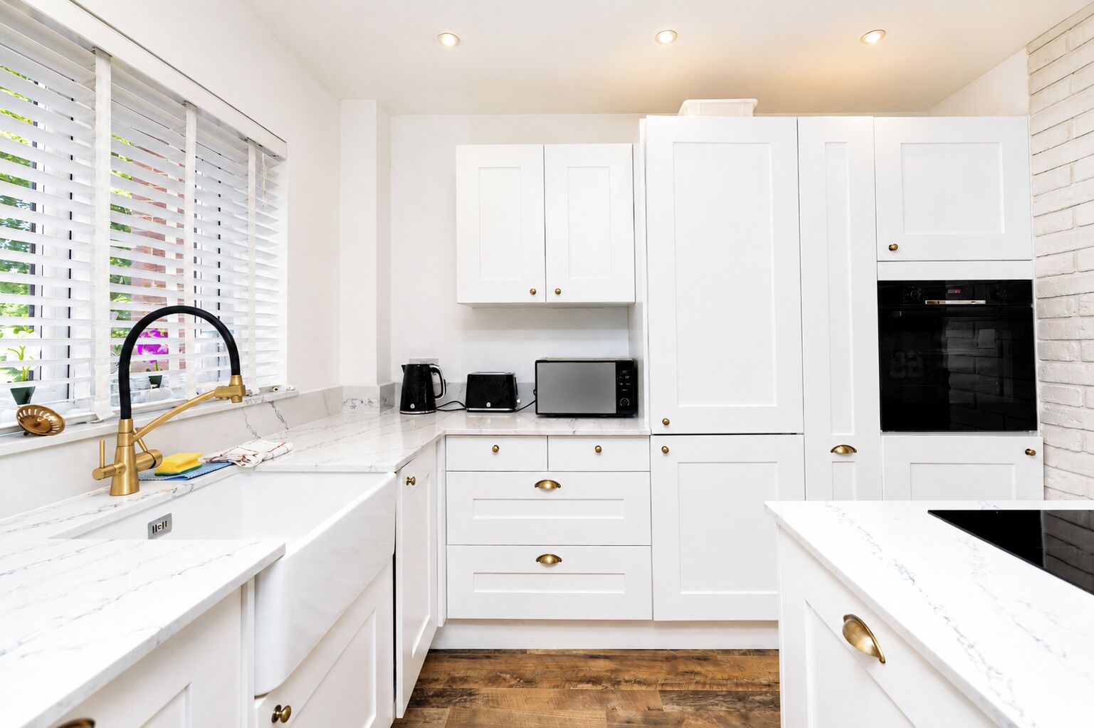 A modern kitchen with white cabinetry, a black microwave, and a coffee maker.