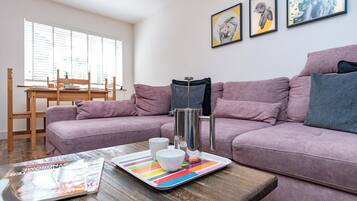 A living room with two sofas, a coffee table, a magazine, and a window with blinds.