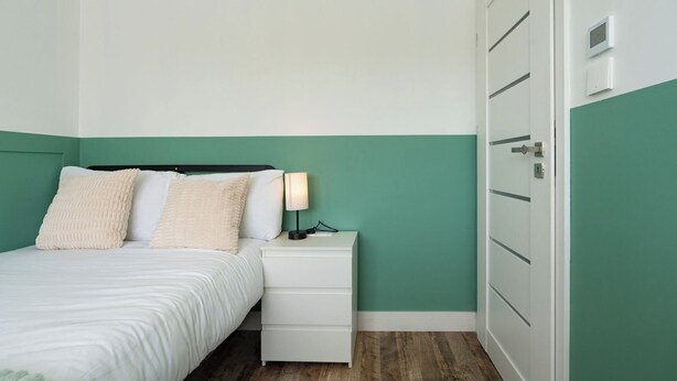 Un dormitorio con cama, mesita de noche, lámpara y armario.