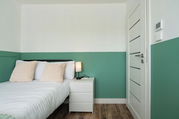 A bedroom with a bed, bedside table, lamp, and a wardrobe.