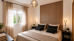 A bedroom with a bed, two bedside tables, a hanging light fixture, a window with curtains, and a wall panel. - Arenal Golf, with private garden, swimming pool, BBQ (Benalmádena)