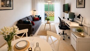 A modern living room with a sofa, dining table, and a desk with a computer. - Arenal Golf, with private garden, swimming pool, BBQ (Benalmádena)