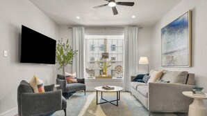 A modern living room with a flat-screen TV, two sofas, a coffee table, and a ceiling fan. - The Cove:2 bdrm, 4 minute walk to A&M (College Station)