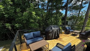 Une terrasse en bois aménagée avec du mobilier d’extérieur, notamment un canapé, des fauteuils et une table.