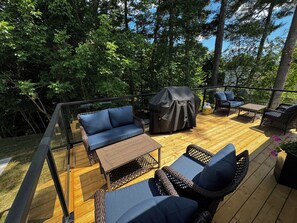 Eine Holzterrasse mit Gartenmöbeln, darunter eine Sitzecke, Stühle und ein Tisch.