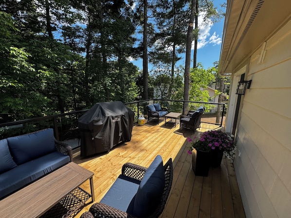 An outdoor deck with a barbecue, seating area, and potted plants.
