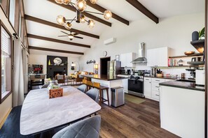 A modern kitchen with a central island, built-in appliances, and a dining area with a wooden table and chairs. - Summer Oasis: Hot Tub, Huge Yard, Pool + Lakes (Long Pond)