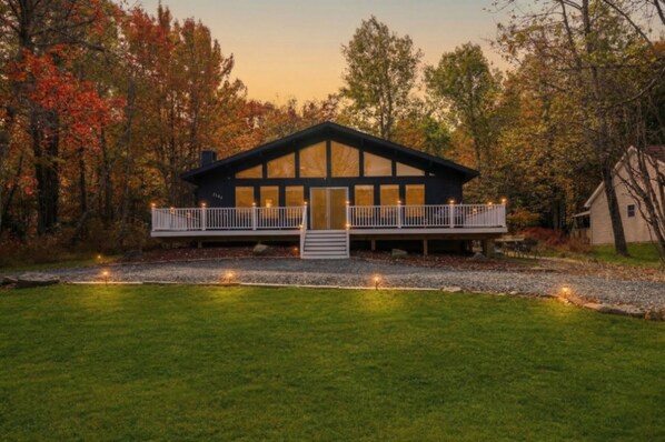 A two-story building with a balcony, surrounded by trees. - Summer Oasis: Hot Tub, Huge Yard, Pool + Lakes (Long Pond)
