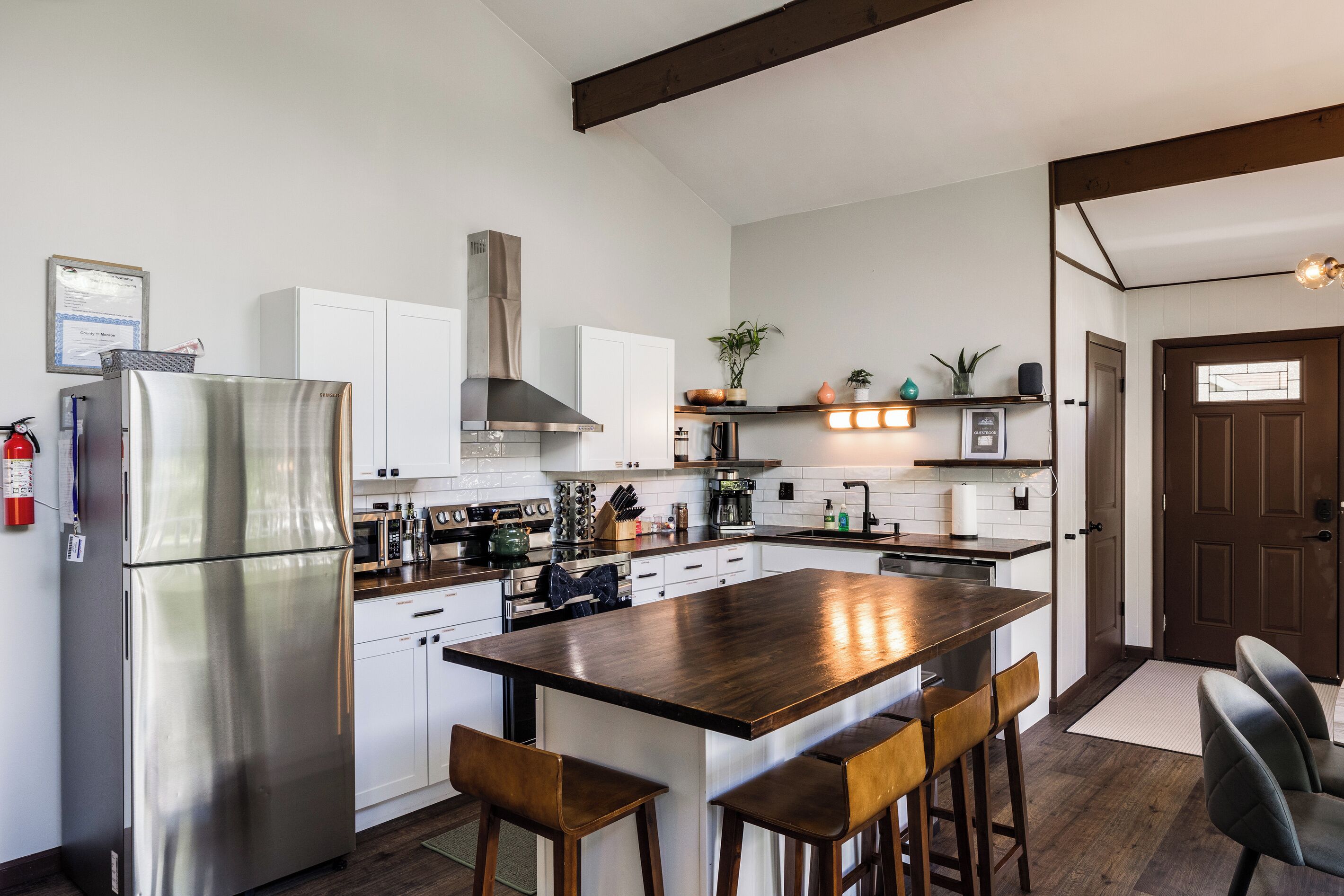 A modern kitchen with a central island, stainless steel appliances, and a wooden ceiling.