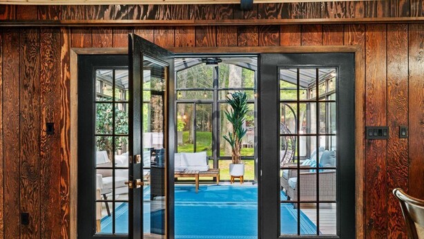 A wooden door leading to a pool area with outdoor furniture and a view of the surrounding greenery. - Hot Tub | Game Room | Fire Pit | Family Friendly (Albrightsville)