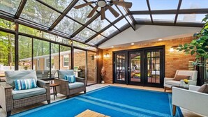 A sunroom with a glass ceiling, wicker furniture, and a blue carpet. - Hot Tub | Game Room | Fire Pit | Family Friendly (Albrightsville)
