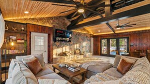 A cozy living room with a fireplace, wooden ceiling, and a Netflix sign. - Hot Tub | Game Room | Fire Pit | Family Friendly (Albrightsville)