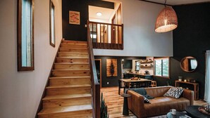 Un vaste espace de vie agrémenté d’un escalier en bois, d’un canapé en cuir, d’une table à manger et d’une cuisine située au fond de la pièce.