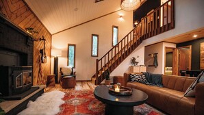 Un salon chaleureux avec une cheminée, un escalier et un canapé en cuir.