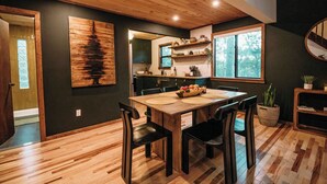 Un coin repas avec une table en bois, des chaises et un panier de fruits.