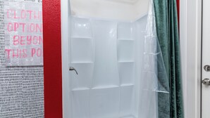 A bathroom with a white shower enclosure, a red wall, and a green curtain. - Lovely 1-bedroom studio with AC in Phoenix (Phoenix)