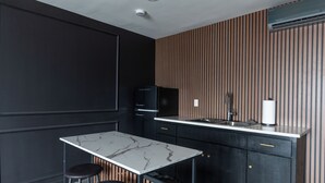 A modern kitchen with a marble countertop, black cabinetry, and a wooden accent wall. - Lovely 1-bedroom studio with AC in Phoenix (Phoenix)