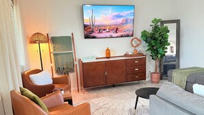 A modern living room with a sofa, chairs, a wooden cabinet, a television, and a potted plant. - 4BR Family & group Oasis in Mesa – Big Backyard & Steps from Sloan Park & ASU!! (Mesa)