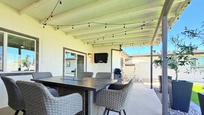 An outdoor patio with a table and chairs, a grill, and potted plants. - 4BR Family & group Oasis in Mesa – Big Backyard & Steps from Sloan Park & ASU!! (Mesa)
