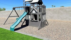 A playground with a slide and climbing structure. - 4BR Family & group Oasis in Mesa – Big Backyard & Steps from Sloan Park & ASU!! (Mesa)