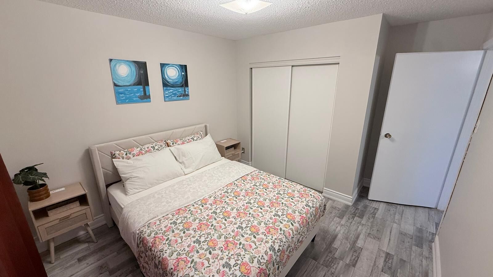 Une chambre à coucher comprenant un lit, une table de chevet, une armoire et deux œuvres d’art murales.