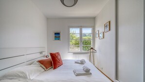 Una camera da letto con un letto, cuscini, una finestra vista, una lampada da terra e un termosifone.