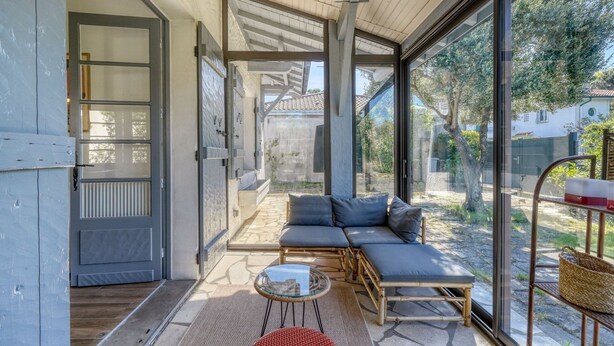 Un interno moderno con una porta vetrata che dà su un patio, un divano, un tavolino e un cesto in vimini.
