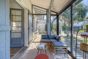 Ein modernes Interieur mit Glastür zu einer Terrassenfläche, einem Sofa, einem kleinen Tisch und einem Korbwannen-Korb.