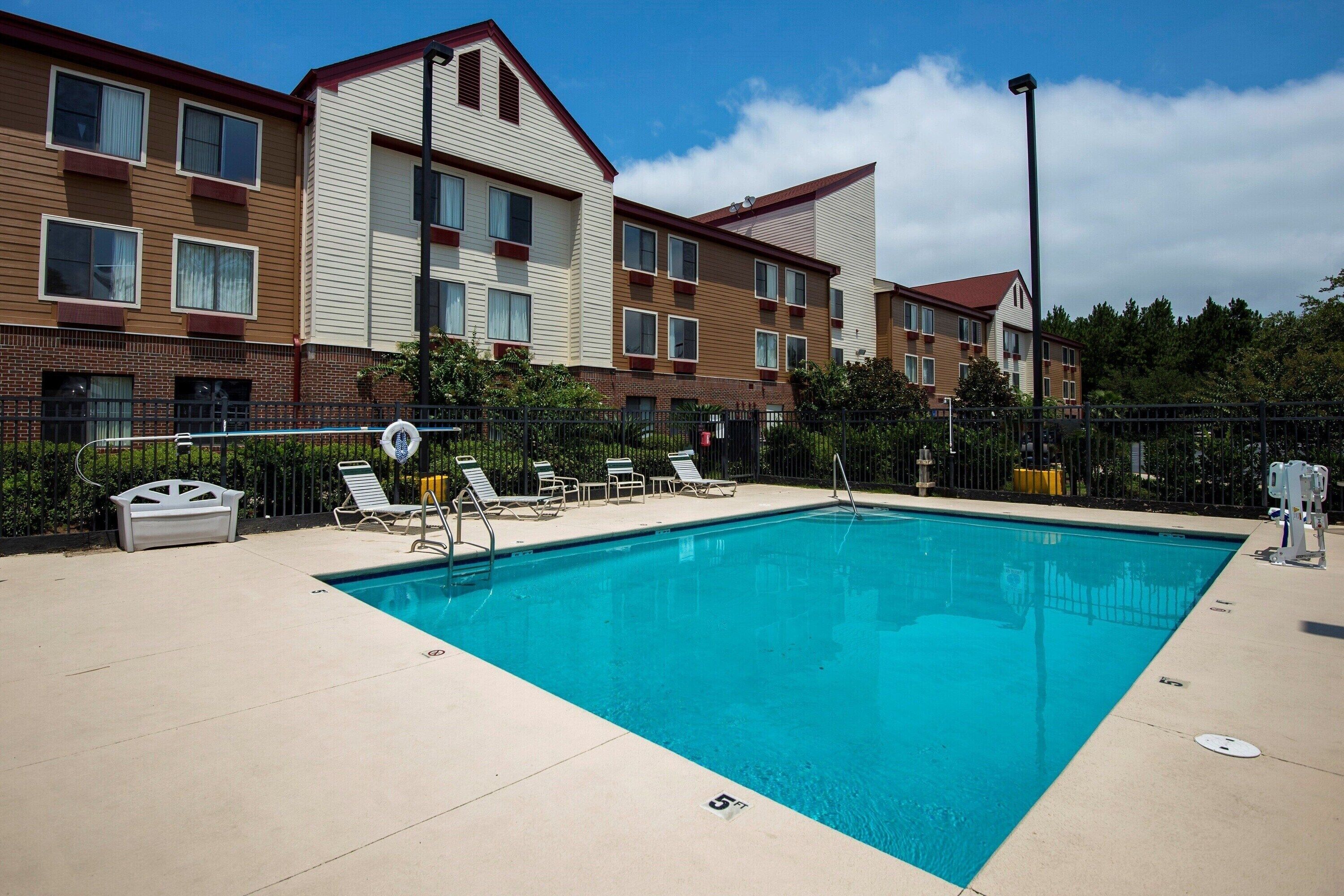 Lounge poolside with plenty of seating and open sky.