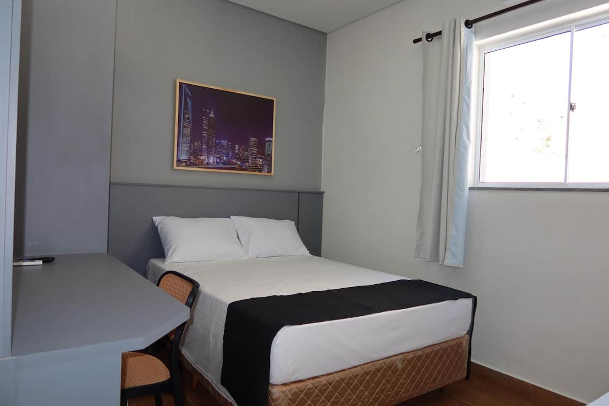 Une chambre d’hôtel avec un lit, un bureau et une fenêtre.