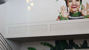 A hotel lobby with a large mural, a staircase, and potted plants.