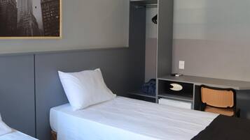 A hotel room with two beds, a desk, a chair, and a wardrobe.