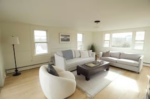 Ein geräumiges Wohnzimmer mit zwei Sofas, einem Couchtisch und einer Stehlampe.