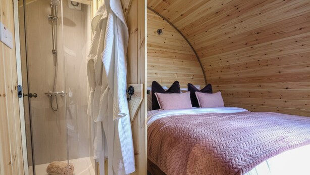 Ein Holzinnenraum mit Dusche, einem Bett mit rosa Decke und Holzboden.