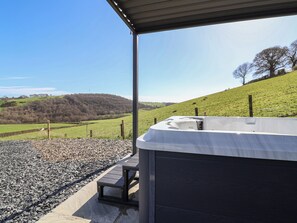 A hot tub under a covered area with a view of a green landscape. - Cennin Pedr (Ruthin)