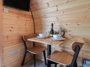 A wooden interior with a table set for two, including a bottle, glasses, and a teapot. - Cennin Pedr (Ruthin)