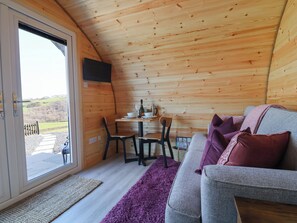 Ein gemütliches Blockhaus-Interieur mit Essbereich, einer Couch und Blick ins Freie.