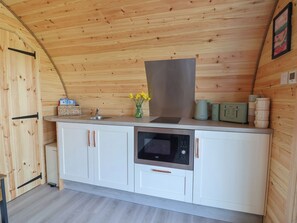 A compact kitchen with a built-in oven, a microwave, and a sink. - Cennin Pedr (Ruthin)