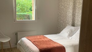 Une chambre à coucher avec un lit, une fenêtre, un radiateur et une chaise.