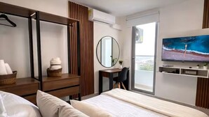 Ein modernes Hotelzimmer mit einem Bett, einem Schreibtisch, einem Sessel, einem Fernseher und einem Balkon.