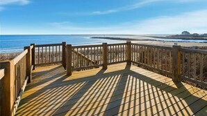 A wooden deck with a view of the beach and ocean.