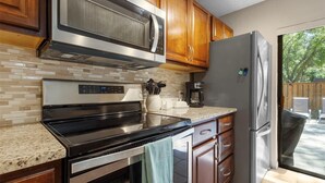 A kitchen with stainless steel appliances, wooden cabinets, a tiled backsplash, and a refrigerator. - Beautiful Townhome/Fully Furnished in the heart of Palm Harbor. (Palm Harbor)