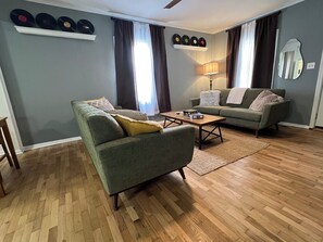 Ein Wohnzimmer mit Sofa, Sessel, Couchtisch und Lampe.