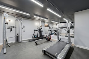 Academia com esteiras, aparelhos de musculação e um espelho grande.