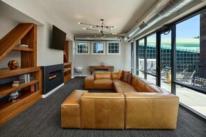 Una sala moderna con un amplio sofá modular, una chimenea y un ventanal con vistas al exterior.