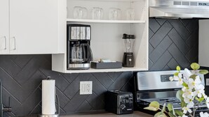 Uma cozinha com armários brancos, cafeteira, liquidificador e torradeira na bancada.