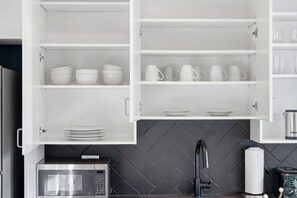 A kitchen with white cabinets, a microwave, a kettle, and a toaster.