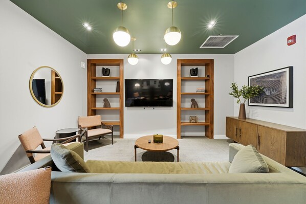A modern living room with a sofa, chairs, a coffee table, a TV, and built-in shelving.