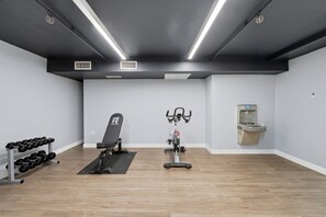 A gym with exercise equipment, a dumbbell rack, and a wall-mounted toilet.