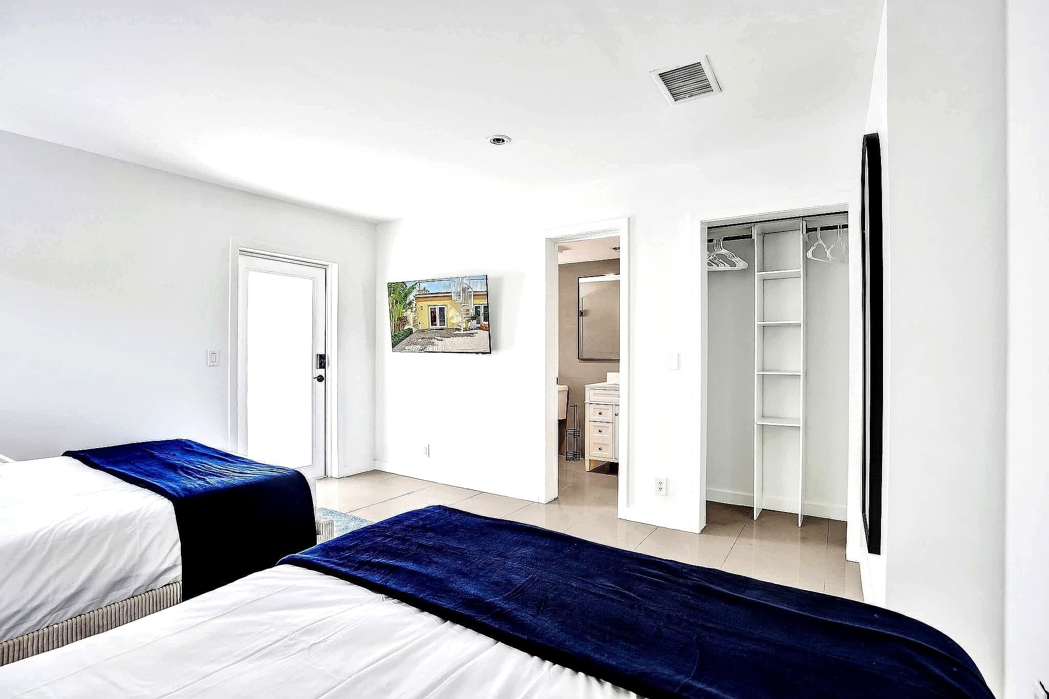 Un dormitorio con dos camas, un armario y una puerta que da al baño.